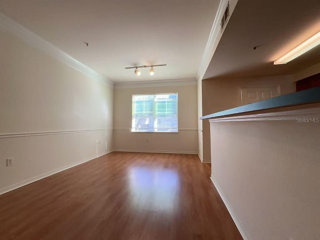 empty room featuring hardwood / wood-style floors, track lighting, and ornamental molding