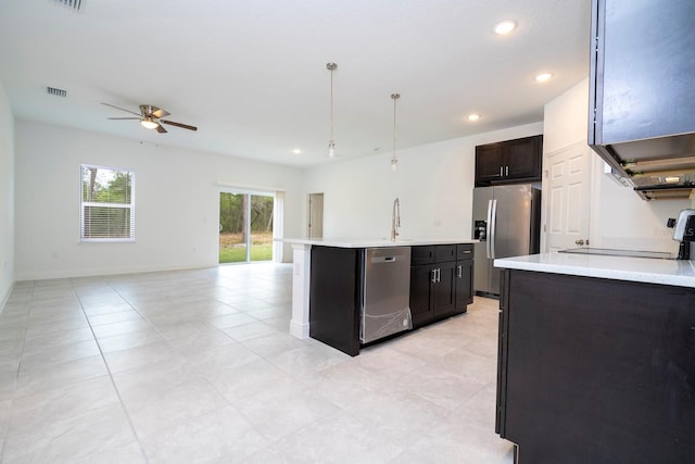 kitchen featuring a center island with sink, sink, ceiling fan, appliances with stainless steel finishes, and decorative light fixtures