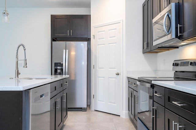 kitchen featuring sink, an island with sink, decorative light fixtures, light tile patterned floors, and appliances with stainless steel finishes