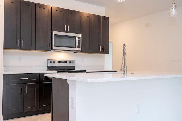 kitchen featuring appliances with stainless steel finishes, dark brown cabinetry, decorative light fixtures, and light tile patterned floors