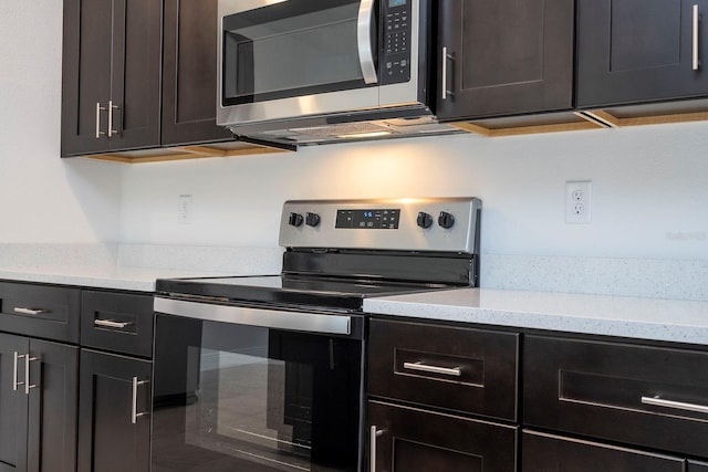 kitchen featuring appliances with stainless steel finishes, dark brown cabinetry, and light stone counters