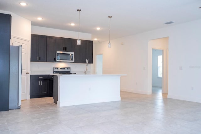 kitchen with hanging light fixtures, a center island with sink, light tile patterned flooring, and stainless steel appliances