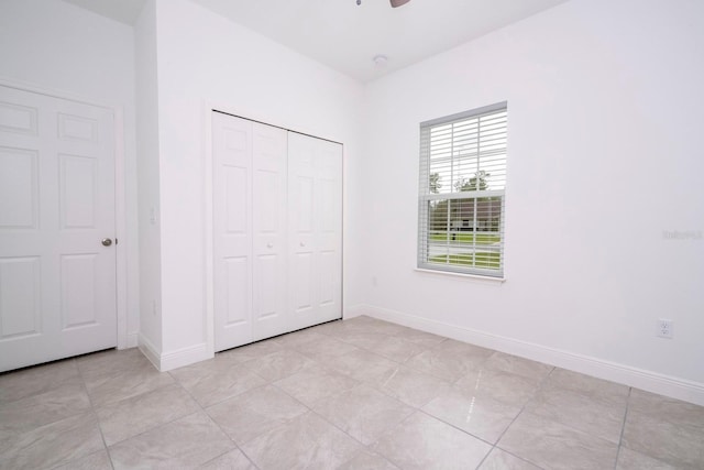 unfurnished bedroom with ceiling fan, a closet, and light tile patterned floors