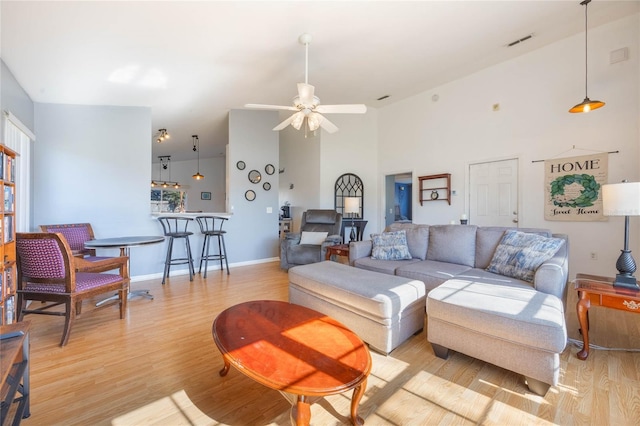 living room with ceiling fan, high vaulted ceiling, and light hardwood / wood-style flooring