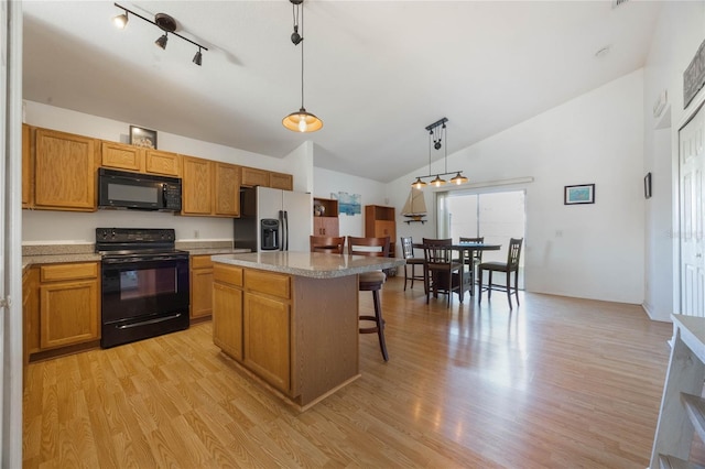 kitchen featuring a kitchen bar, black appliances, light hardwood / wood-style flooring, a center island, and hanging light fixtures