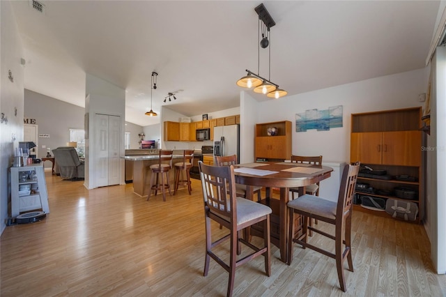 dining space with light hardwood / wood-style flooring and vaulted ceiling