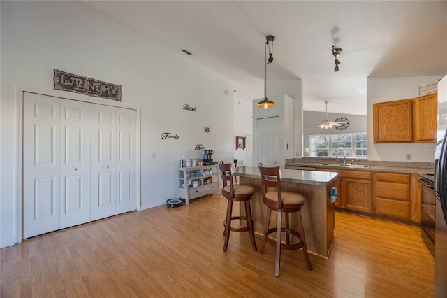 kitchen featuring a breakfast bar, ceiling fan, sink, light hardwood / wood-style flooring, and a center island