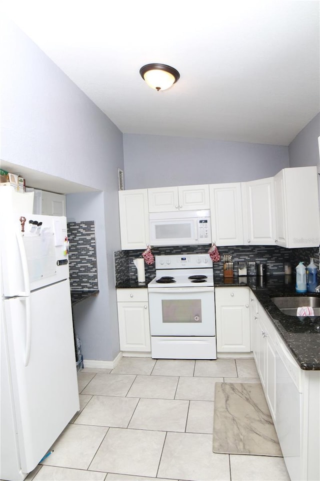 kitchen with sink, white cabinets, dark stone counters, white appliances, and light tile patterned flooring