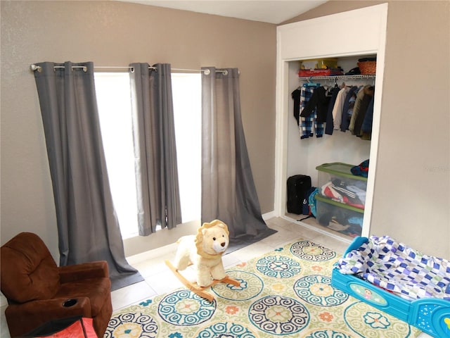 tiled bedroom with multiple windows, vaulted ceiling, and a closet