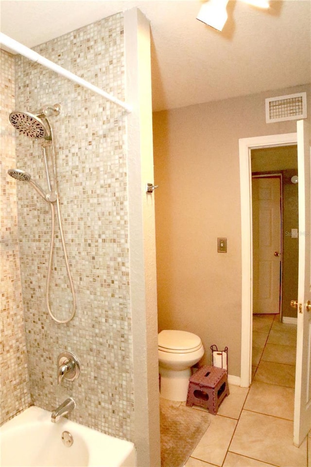 bathroom with tile patterned floors, tiled shower / bath combo, and toilet