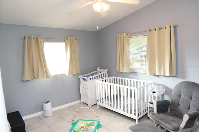 bedroom featuring ceiling fan, light tile patterned flooring, lofted ceiling, and a nursery area