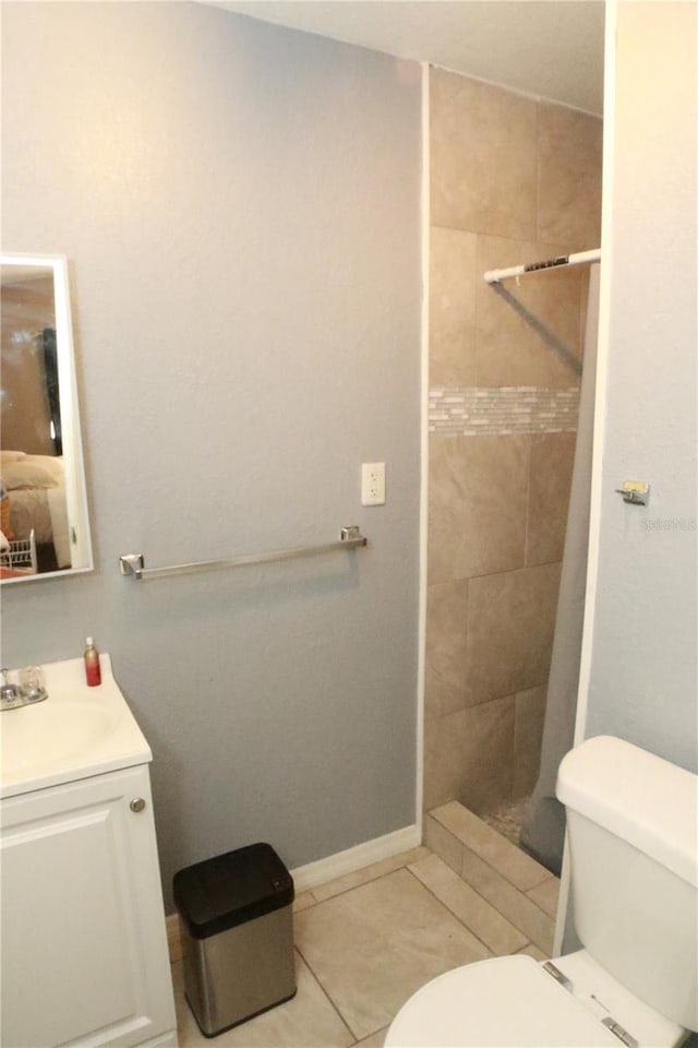 bathroom featuring tile patterned flooring, vanity, toilet, and tiled shower