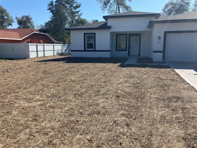 view of front of property featuring a garage, fence, and stucco siding