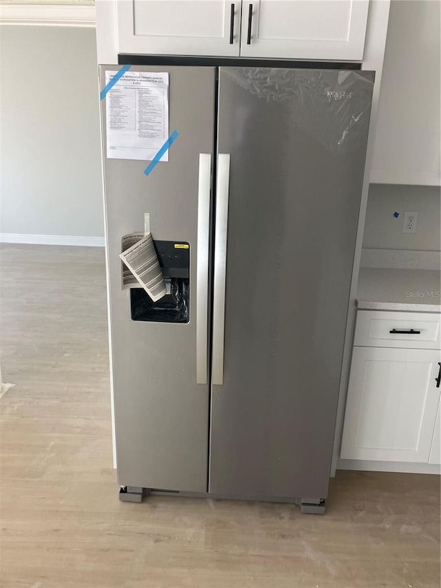 room details featuring white cabinetry, stainless steel refrigerator with ice dispenser, and light countertops