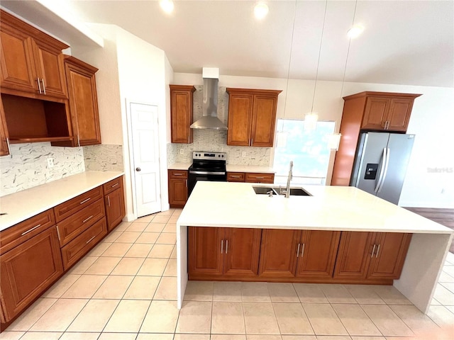 kitchen featuring appliances with stainless steel finishes, sink, wall chimney range hood, pendant lighting, and a center island with sink