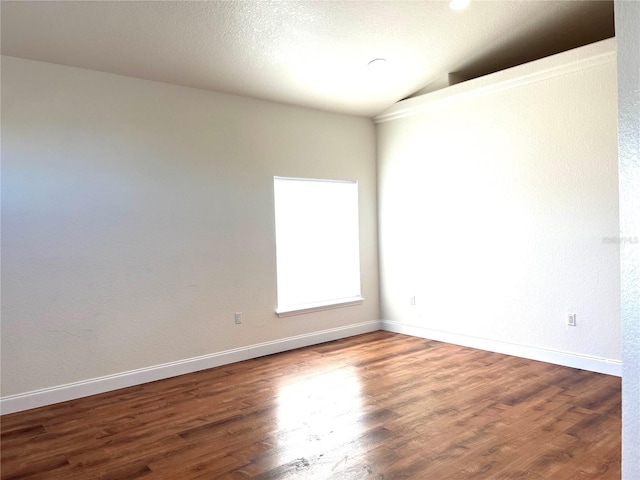 spare room with a textured ceiling, vaulted ceiling, and hardwood / wood-style flooring