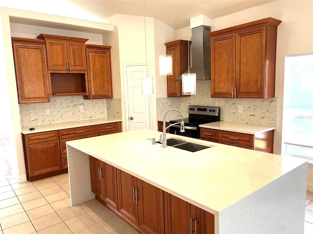 kitchen with electric range, hanging light fixtures, wall chimney range hood, tasteful backsplash, and an island with sink