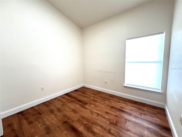 unfurnished room featuring dark hardwood / wood-style floors and vaulted ceiling