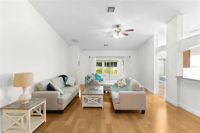 living room with a textured ceiling, light hardwood / wood-style flooring, and ceiling fan