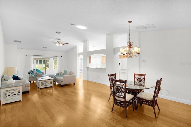 dining space with vaulted ceiling, ceiling fan with notable chandelier, and hardwood / wood-style flooring