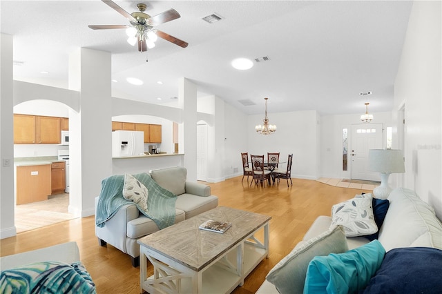 living room with ceiling fan with notable chandelier and light hardwood / wood-style flooring