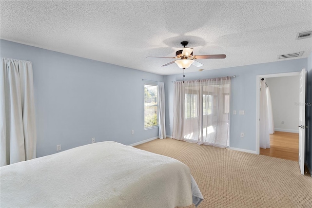 carpeted bedroom featuring ceiling fan and a textured ceiling