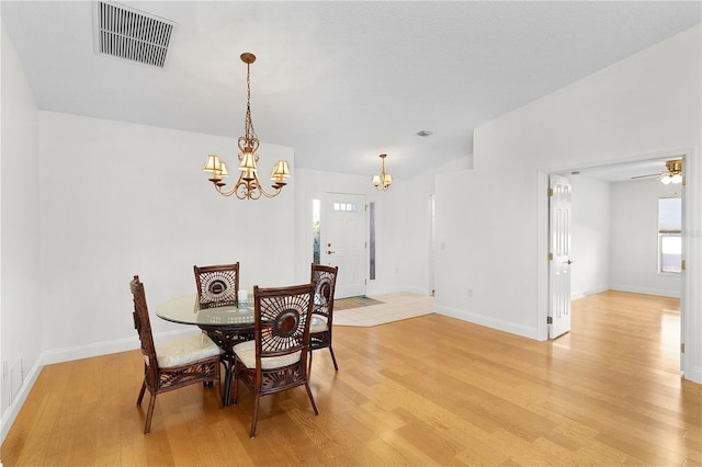 dining space with ceiling fan with notable chandelier, light hardwood / wood-style floors, and a healthy amount of sunlight