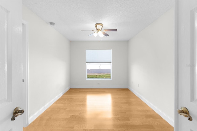 unfurnished room featuring a textured ceiling, light wood-type flooring, and ceiling fan