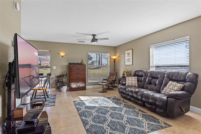 tiled living room with a wealth of natural light, ceiling fan, and a textured ceiling