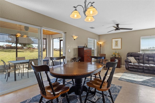 dining area with a textured ceiling and ceiling fan with notable chandelier