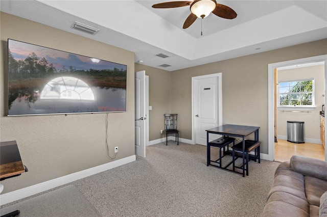 interior space featuring a raised ceiling, ceiling fan, and carpet flooring