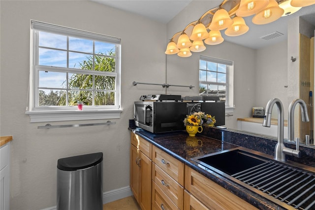 kitchen featuring sink, hanging light fixtures, and dark stone counters