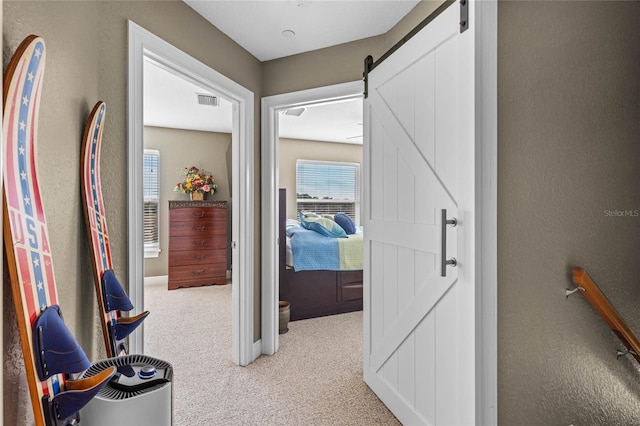 hall with a barn door and light carpet