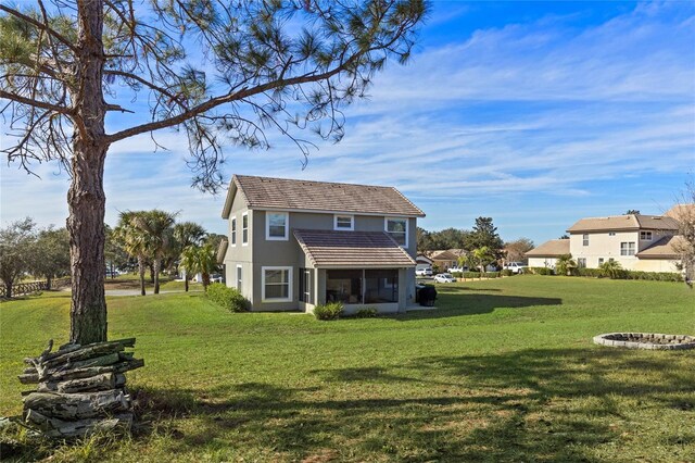 back of property featuring a sunroom and a lawn