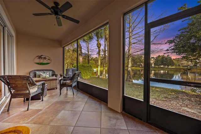 sunroom with ceiling fan and a water view