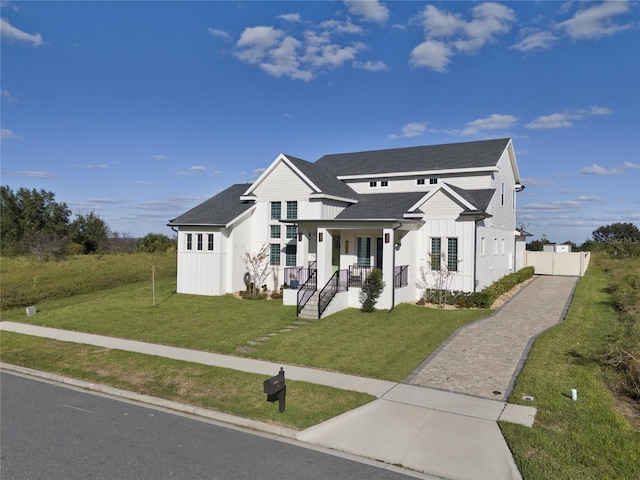 3705 Ridge Run Dr, Minneola, FL 34715 - modern inspired farmhouse featuring roof with shingles, board and batten siding, a porch, a front yard, and driveway