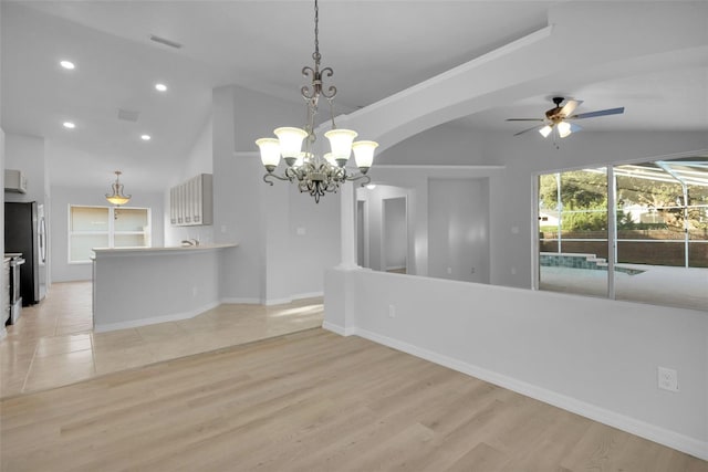 spare room with lofted ceiling, ceiling fan with notable chandelier, and light wood-type flooring