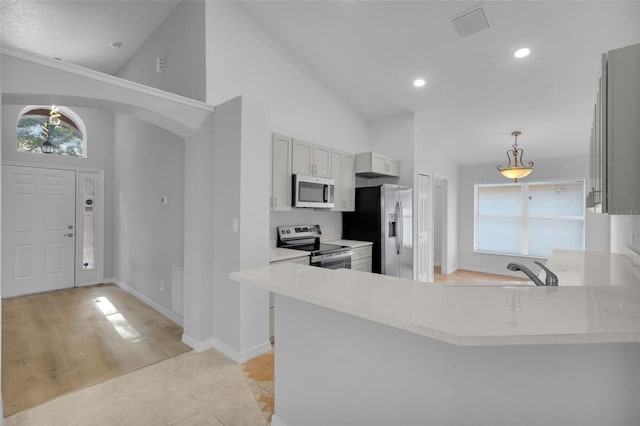 kitchen with kitchen peninsula, appliances with stainless steel finishes, high vaulted ceiling, and light tile patterned floors