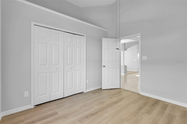 unfurnished bedroom featuring crown molding, a closet, and light hardwood / wood-style flooring