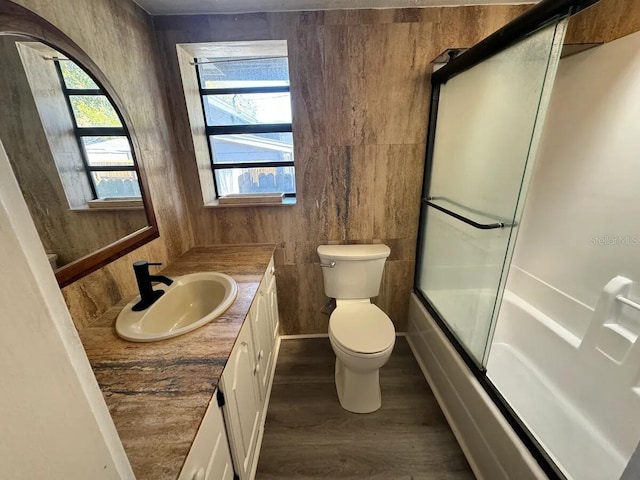 full bathroom with hardwood / wood-style floors, vanity, toilet, and enclosed tub / shower combo