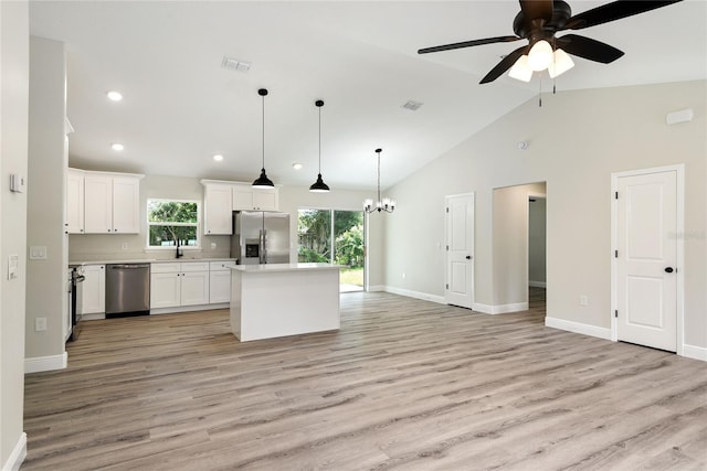 kitchen with a center island, white cabinets, ceiling fan with notable chandelier, appliances with stainless steel finishes, and decorative light fixtures