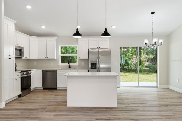 kitchen featuring white cabinets, appliances with stainless steel finishes, pendant lighting, and sink