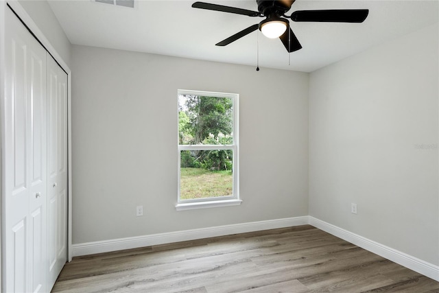 unfurnished bedroom with ceiling fan, light wood-type flooring, and a closet