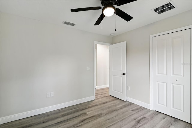 unfurnished bedroom featuring ceiling fan, a closet, and light wood-type flooring