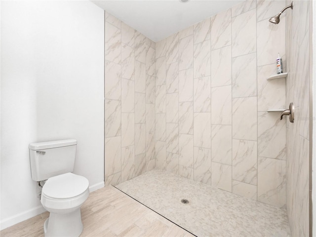 bathroom with a tile shower, toilet, and hardwood / wood-style floors