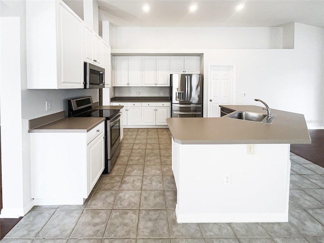 kitchen featuring white cabinets, appliances with stainless steel finishes, a kitchen island with sink, and sink