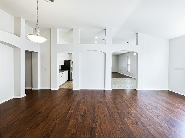 unfurnished living room featuring dark hardwood / wood-style flooring and high vaulted ceiling