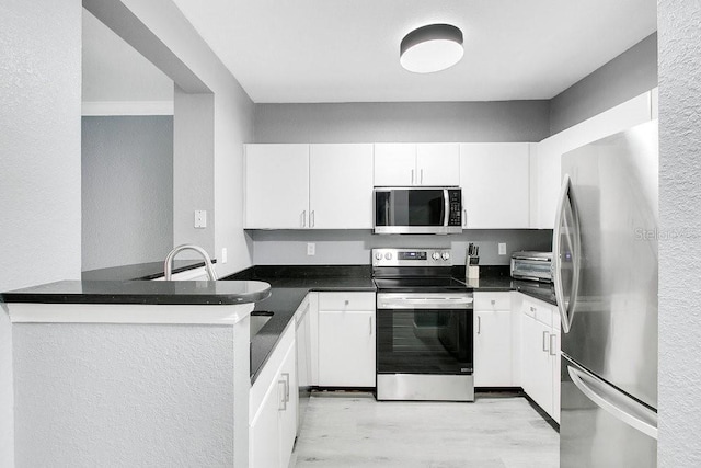 kitchen with white cabinetry, sink, stainless steel appliances, kitchen peninsula, and light wood-type flooring