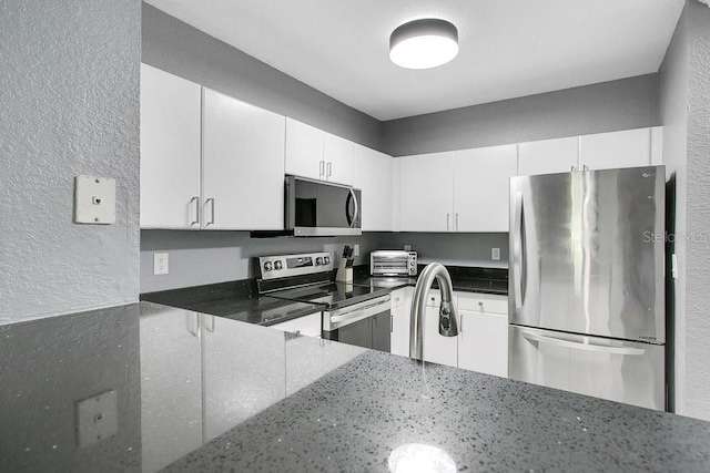 kitchen with dark stone countertops, sink, white cabinets, and stainless steel appliances