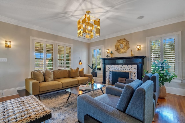 living room featuring a tile fireplace, an inviting chandelier, ornamental molding, and wood-type flooring